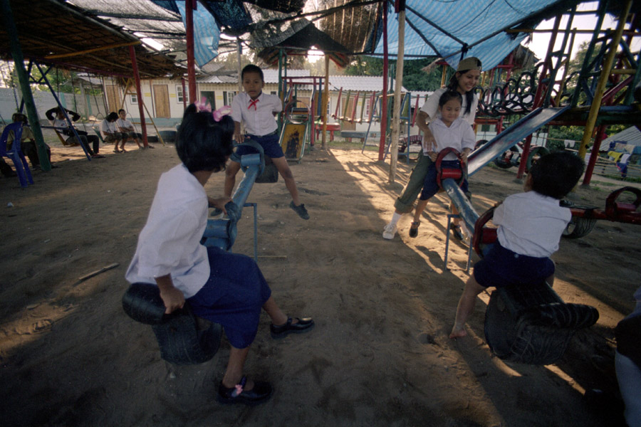Agape School and Orphanage: children play with a continuing-ed student from Wide Horizons. Agape is one of the more well-supported migrant schools, where children wear uniforms similar to those of Thai students, and have  a beautiful playground featuring these seesaws, carousels, and jungle gyms.<br><br>**NOTE: Agape faced scandal in 2013 when its then-revered headmaster was accused of molestation and fled to Myanmar rather than face the police. The former headmaster spoke English well and solicited a great deal of support from foreigners, continuing to do so from unsuspecting friends after leaving Thailand.