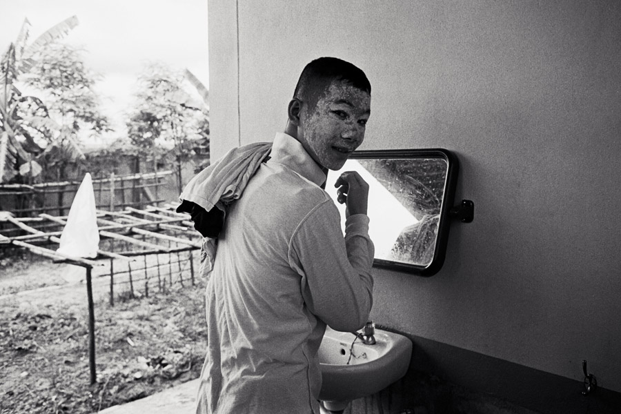Holy Infant Orphanage: a student applies the traditional Burmese cosmetic <i>thanaka</i> to his face. Thanaka is made from powdered tree bark, and can be applied in unique designs. Generally males wear it more sloppily as they get older and no longer have help with application.