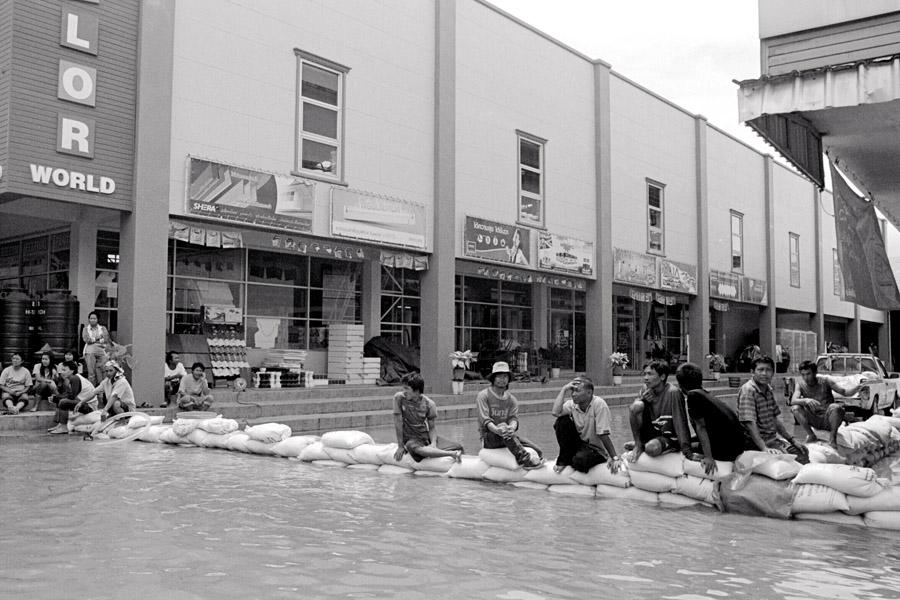 2011: this year flooding was 'normal' level, more an inconvenience rather than causing serious damage. Here, the Burmese staff of a home-improvement store sit along a temporary wall formed to help with the flooding.
