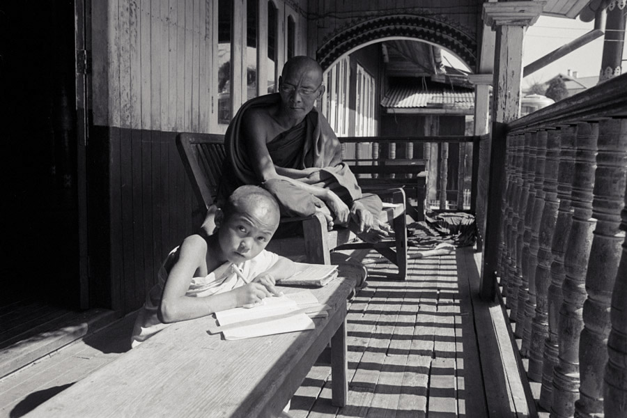 Namshan, Northern Shan State 2011: young novice-to-be studies with his monk mentor. Kids his age are often taken into monasteries after becoming orphaned, and the white-robed boys are not held to rules as strictly as red-robed novices.