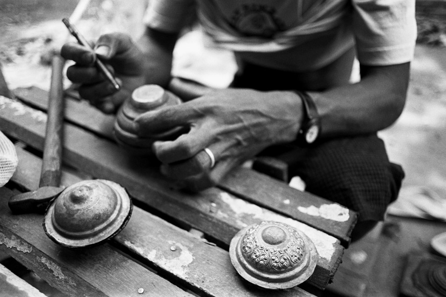 Sagaing, 2012: crafting silver pots. The pot lids are filled with what looks like tar, then stuck together. The solid insides makes it easier to gently hammer out a design on the delicate lid.