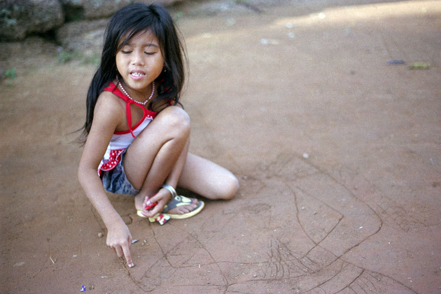 Angkor, Cambodia 2012: young girl drawing in the sand, asking for candy at Banteay Srei temple. Yes, she knew how to ask in Chinese. No, I don't know if she was drawing because she was bored while begging, or thought that people would be inclined to give her candy because she was drawing. Would have been a nice time to have a guide.